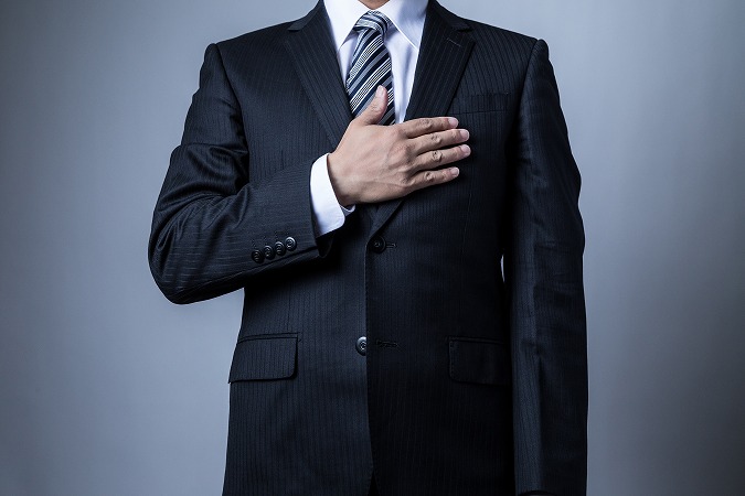 胸に手を当てる男性